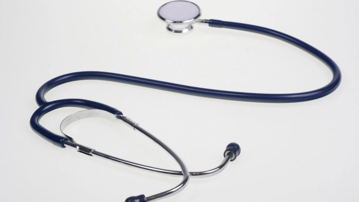 A dark blue stethoscope resting on a plain white surface